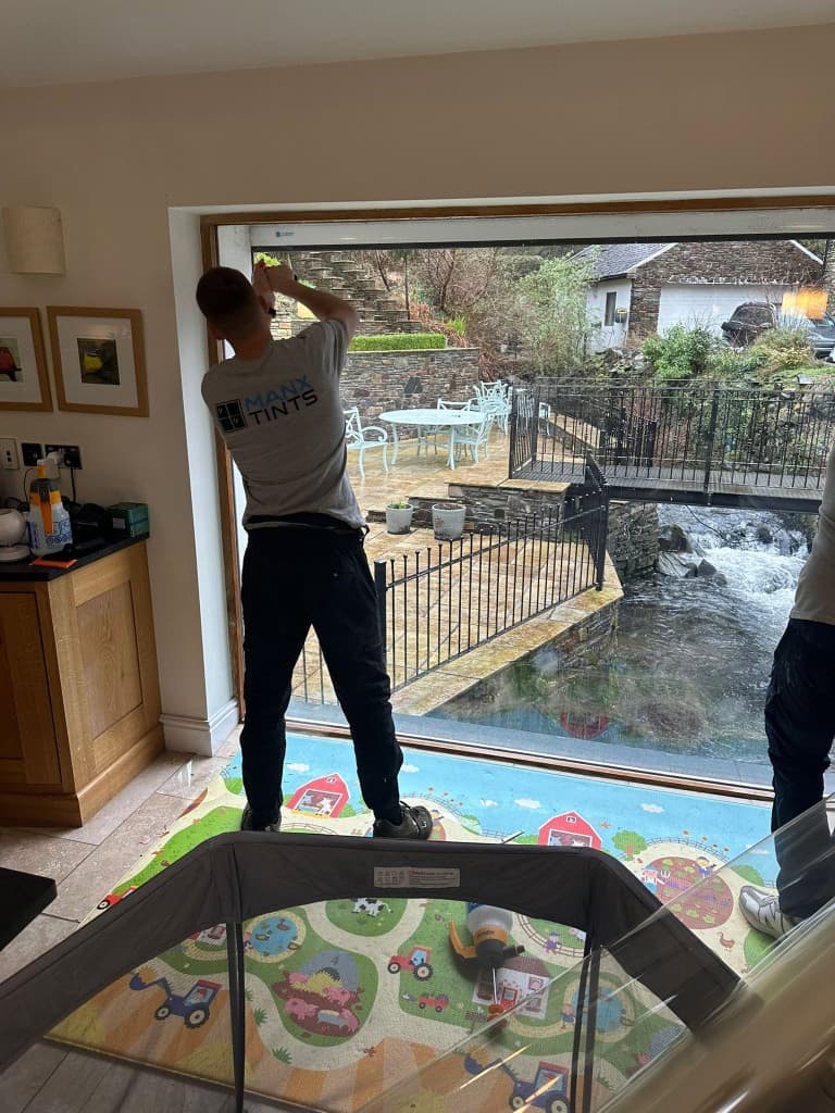 A ManxTints installer applying window film to a residential patio door