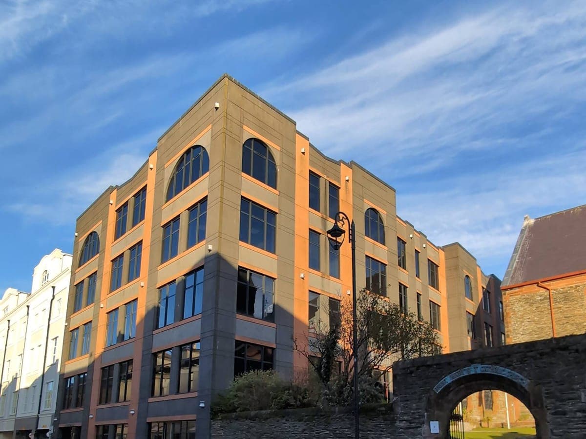 A corner office building with film fitted to its arched windows